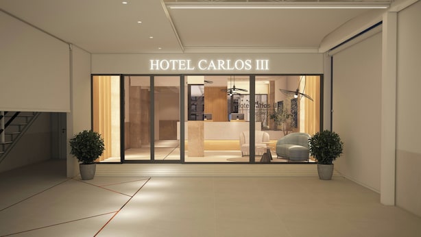 Entrada de hotel con mostrador de recepción, zona de estar y plantas en macetas.