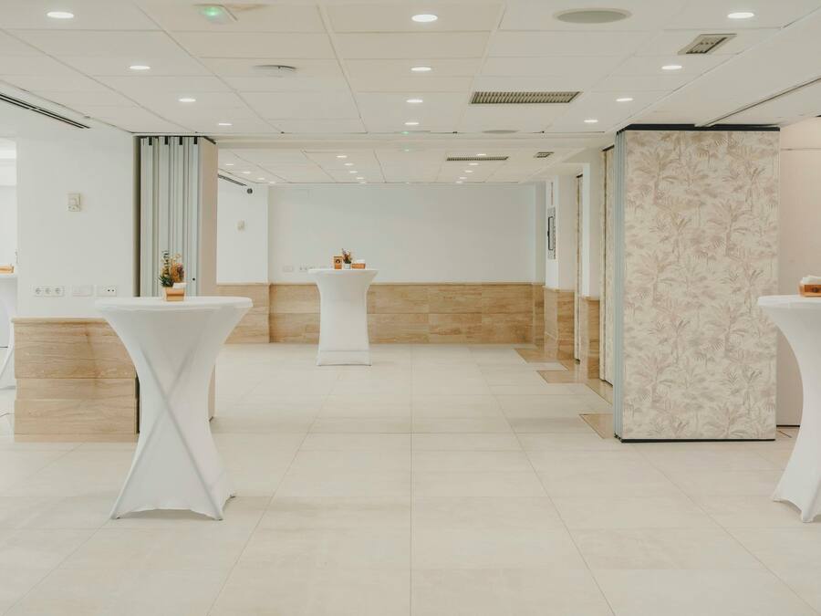 A modern hotel lobby with white tables, a reception desk, and a patterned wall.