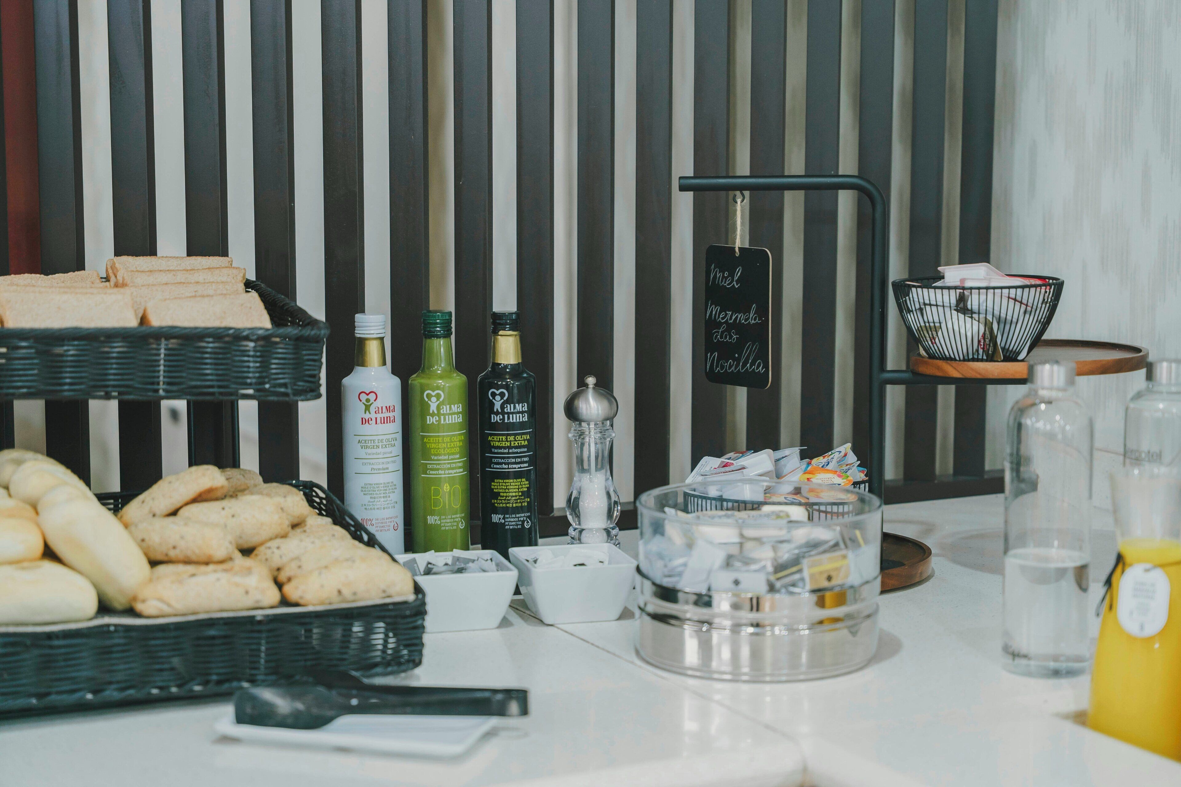 A breakfast buffet with bread, pastries, and condiments.