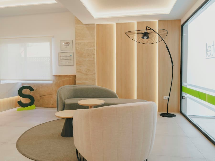 Un espace de bureau moderne doté d’une grande fenêtre, d’un bureau réglable en hauteur, d’une table ronde et d’un canapé.