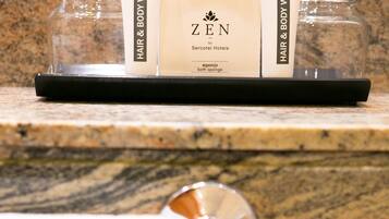 A bathroom counter with a tray holding a Zen brand hair and body wash, a bath sponge, and a glass jar.