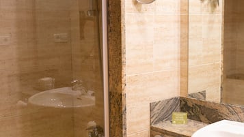 A bathroom with a glass-enclosed shower, a sink, and a mirror.