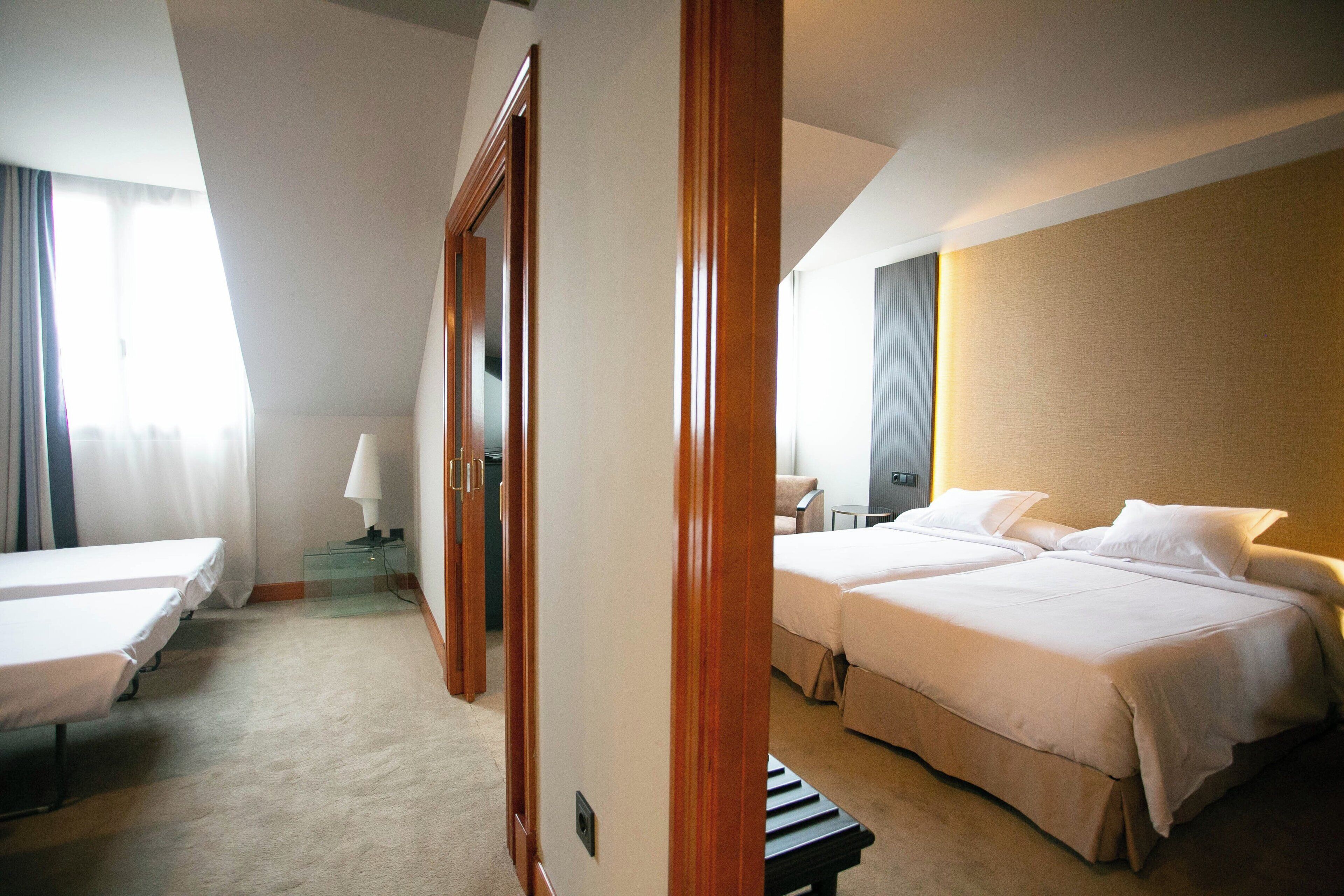 Ein Hotelzimmer mit zwei Betten, einem Schreibtisch und einem Stuhl.
