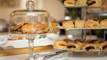 Een buffet met een verscheidenheid aan gebak en koekjes, gepresenteerd op een glazen etagère.