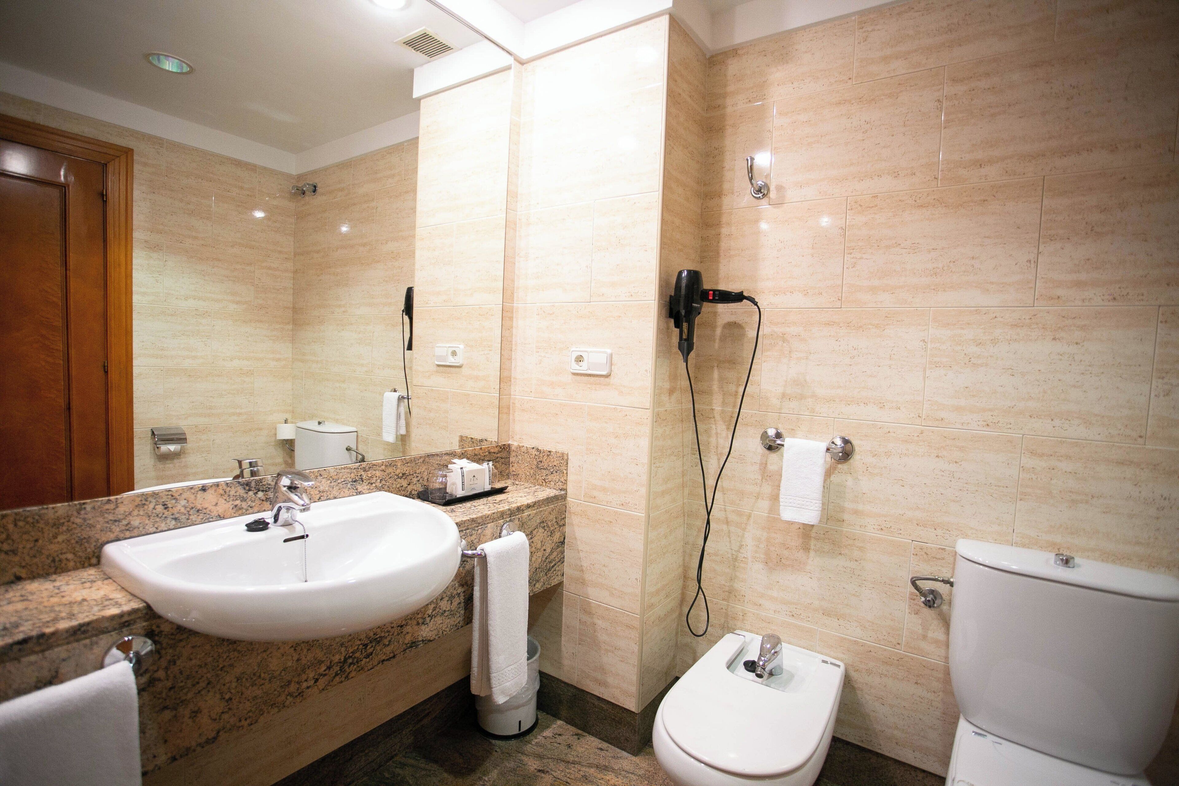 A modern bathroom with a sink, toilet, and shower.
