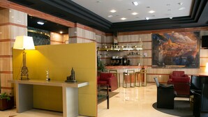 Un vestíbulo moderno de hotel con recepción, zona de estar y bar.