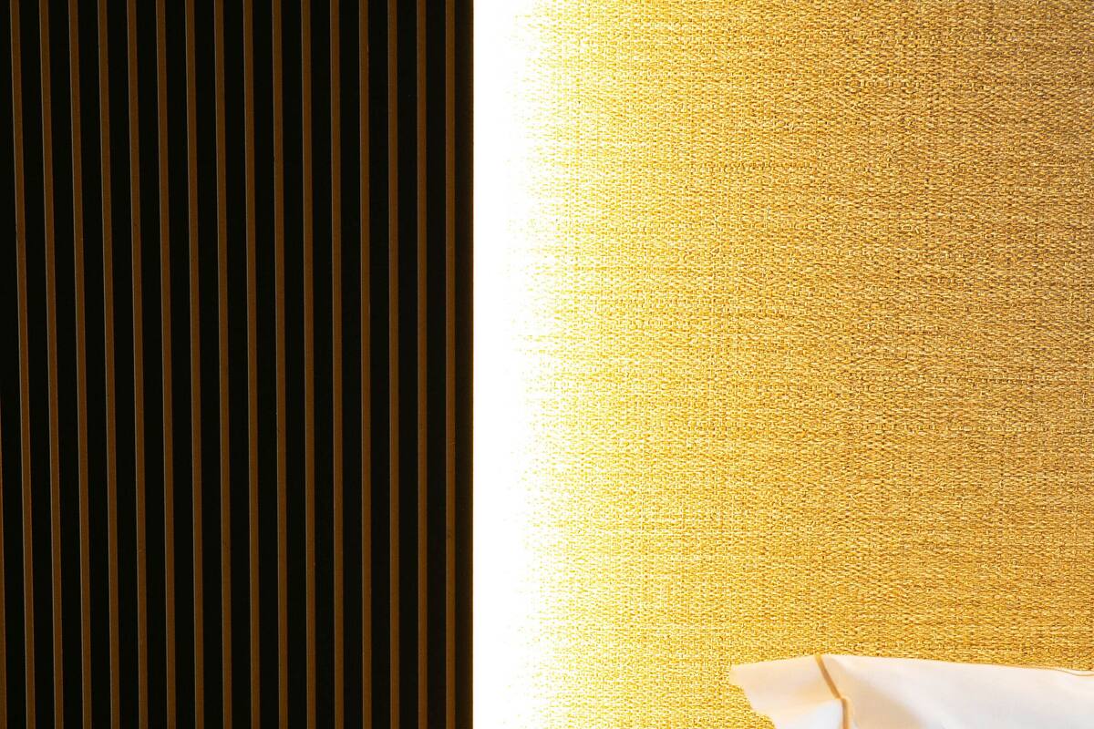 A hotel room with a bed, a bedside table with a glass of water, and a wall-mounted light.