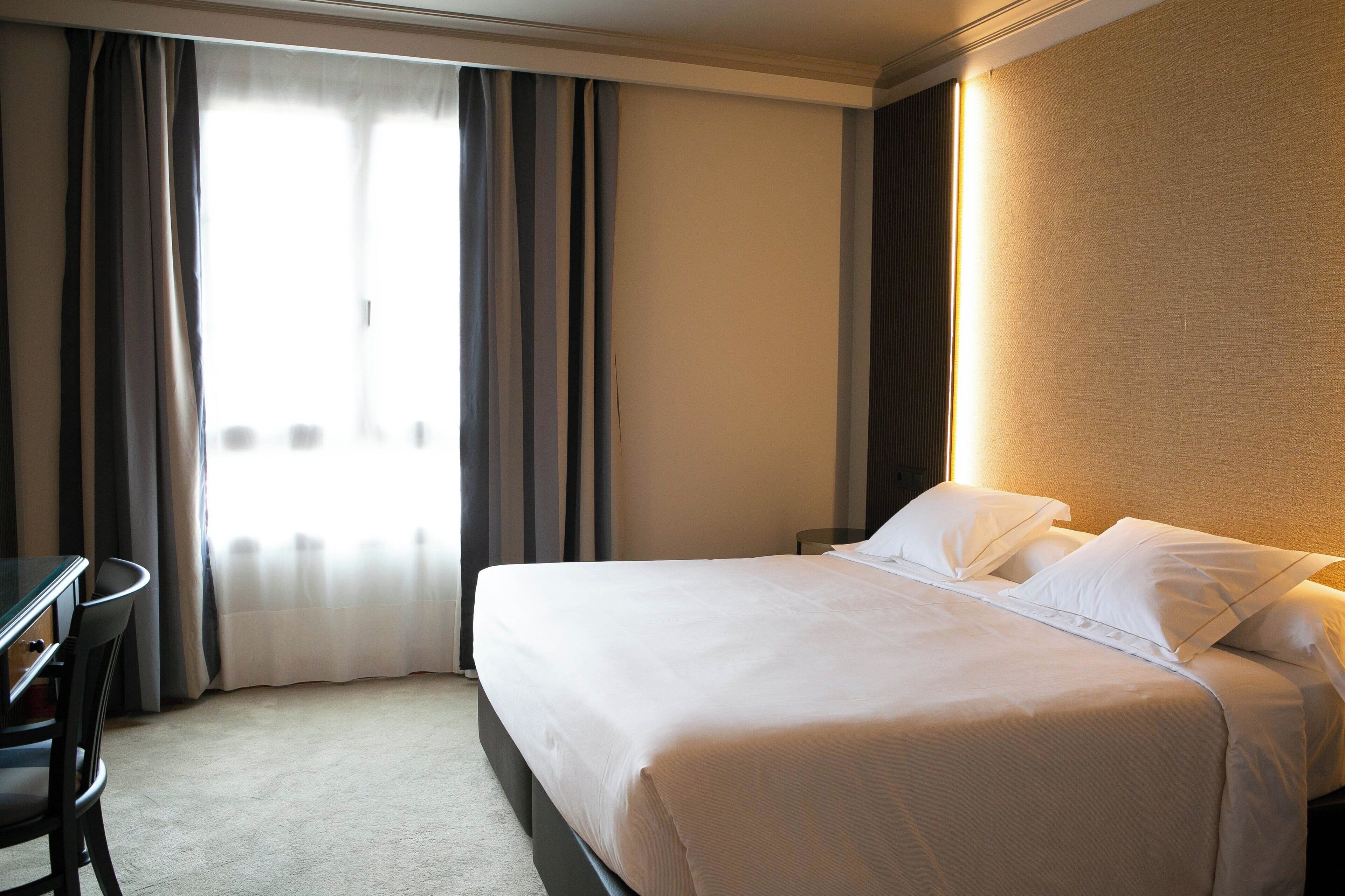 A hotel room with a bed, a desk, and a chair.