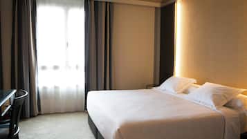 A hotel room with a bed, a desk, and a chair.