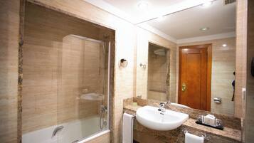 A modern bathroom with a large bathtub, a sink, and a mirror.