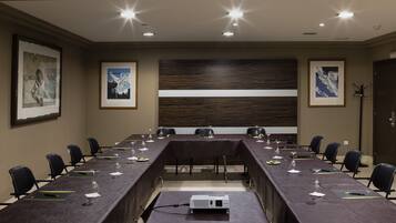 A conference room with a long table, chairs, and a projector.