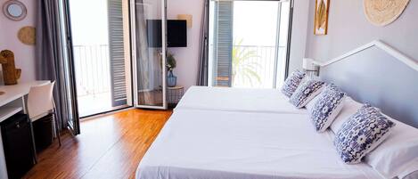 A bedroom with a large bed, a desk, and a sliding glass door leading to a balcony.