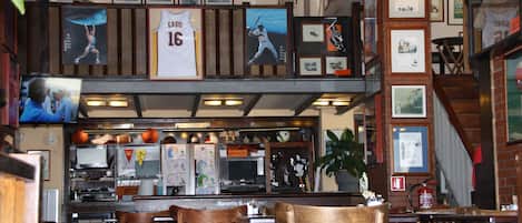 A restaurant with wooden chairs, a counter, and various sports memorabilia on the walls.