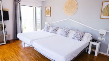 A double bed with white and blue patterned pillows, a bedside table with a phone, and a wall-mounted fan.