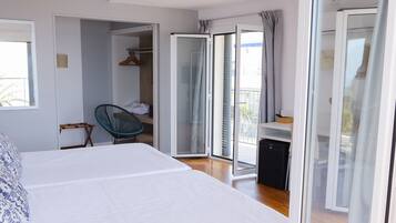 Un dormitorio moderno con una cama grande, una silla, un escritorio y un ventanal corredera que da a un balcón.