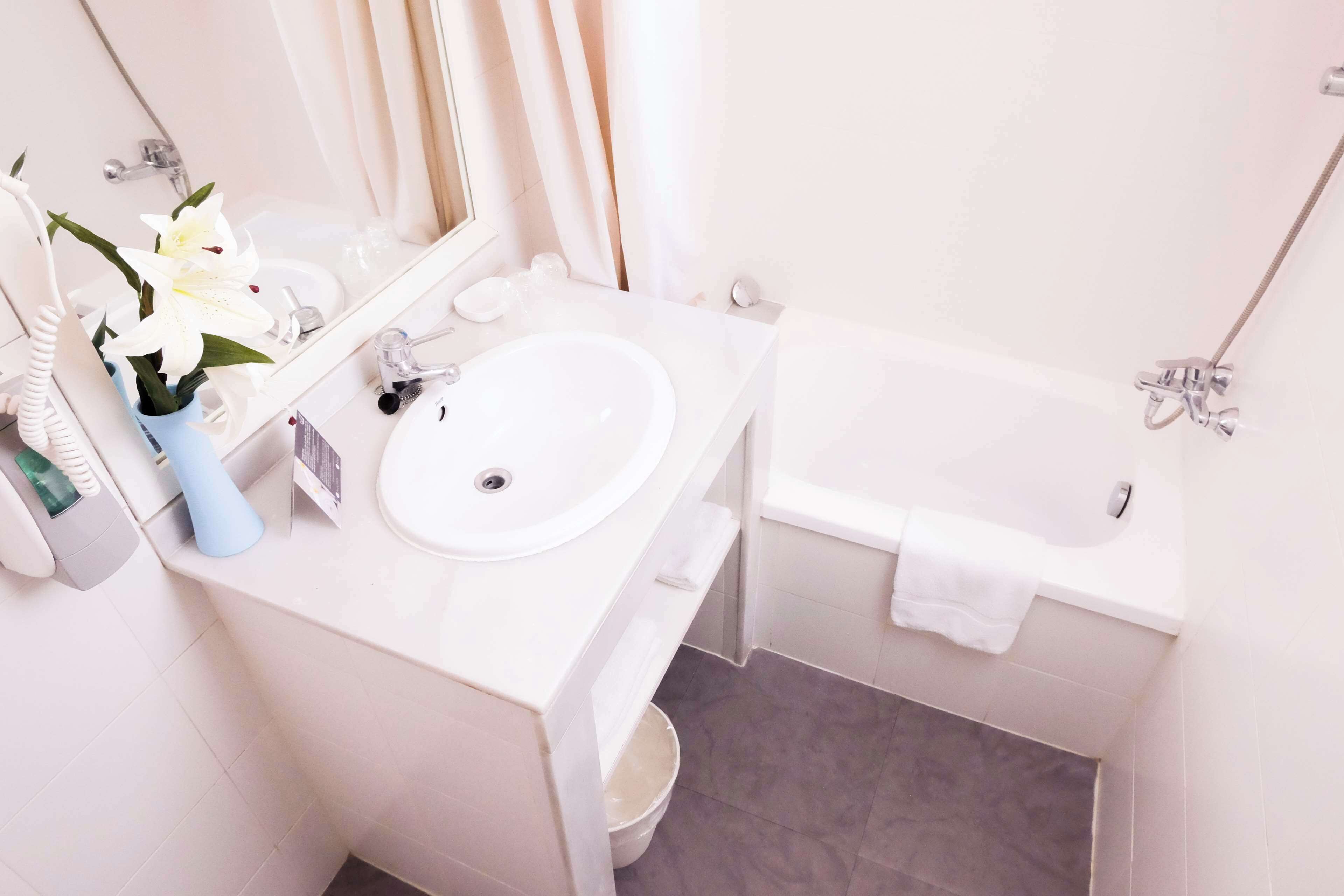 A bathroom with a white sink, mirror, and bathtub.
