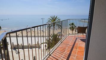 A balcony with a view of a beach and the sea.