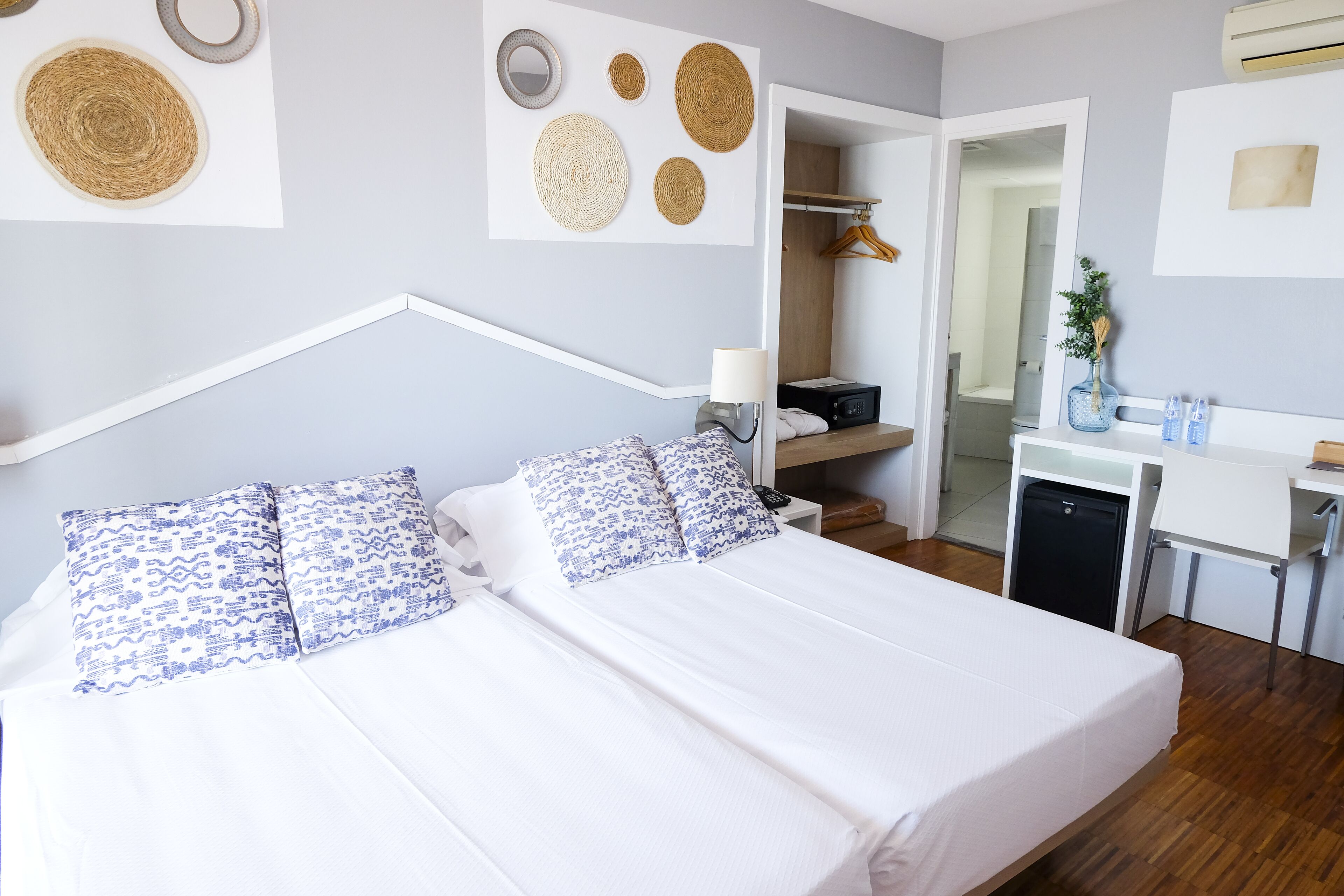 Una habitación de hotel moderna con cama, mesita de noche y zona de escritorio.