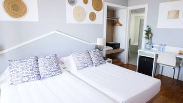 A modern hotel room with a bed, bedside table, and a desk area.