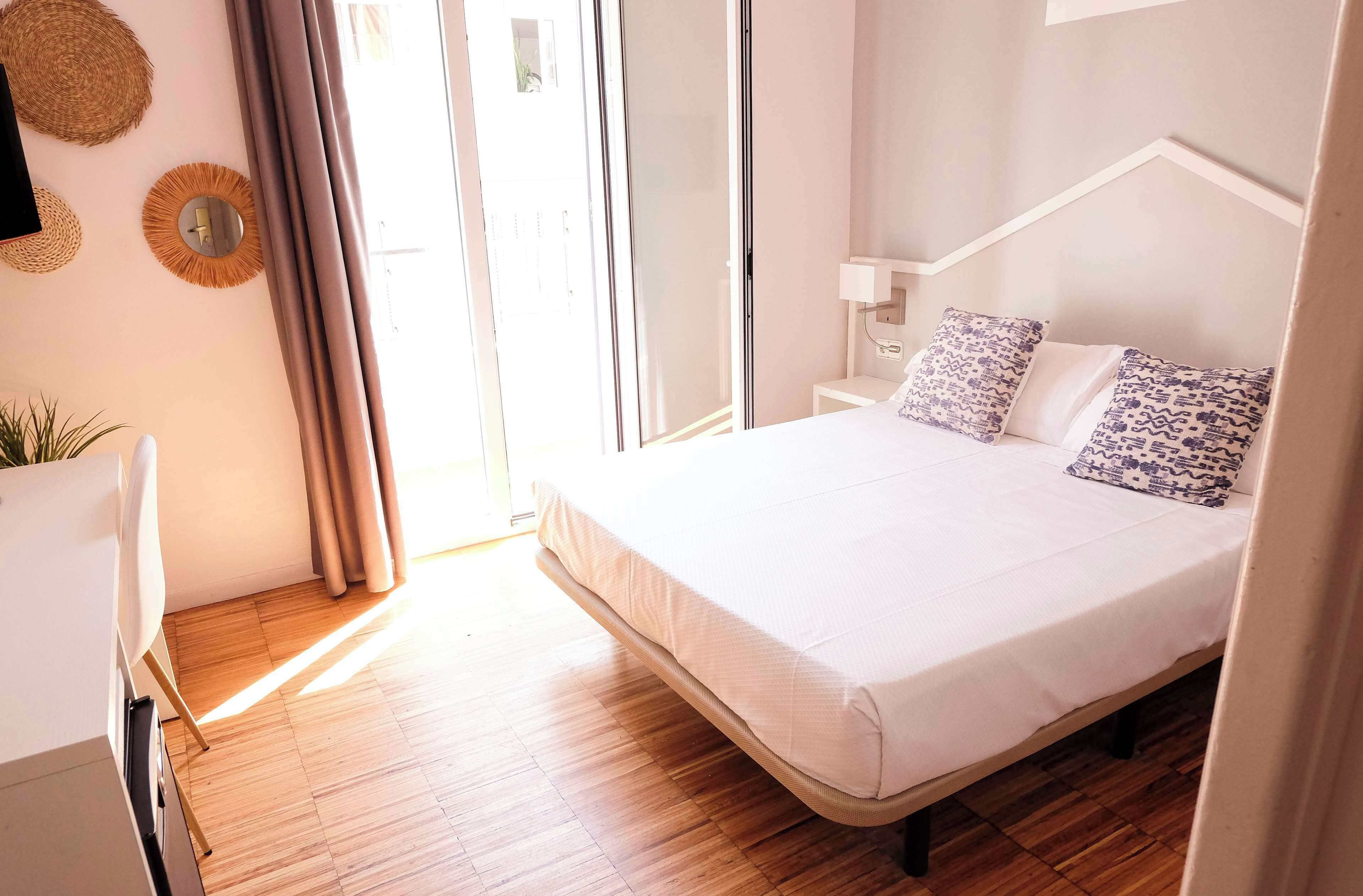 A bedroom with a bed, bedside table, and a window with curtains.