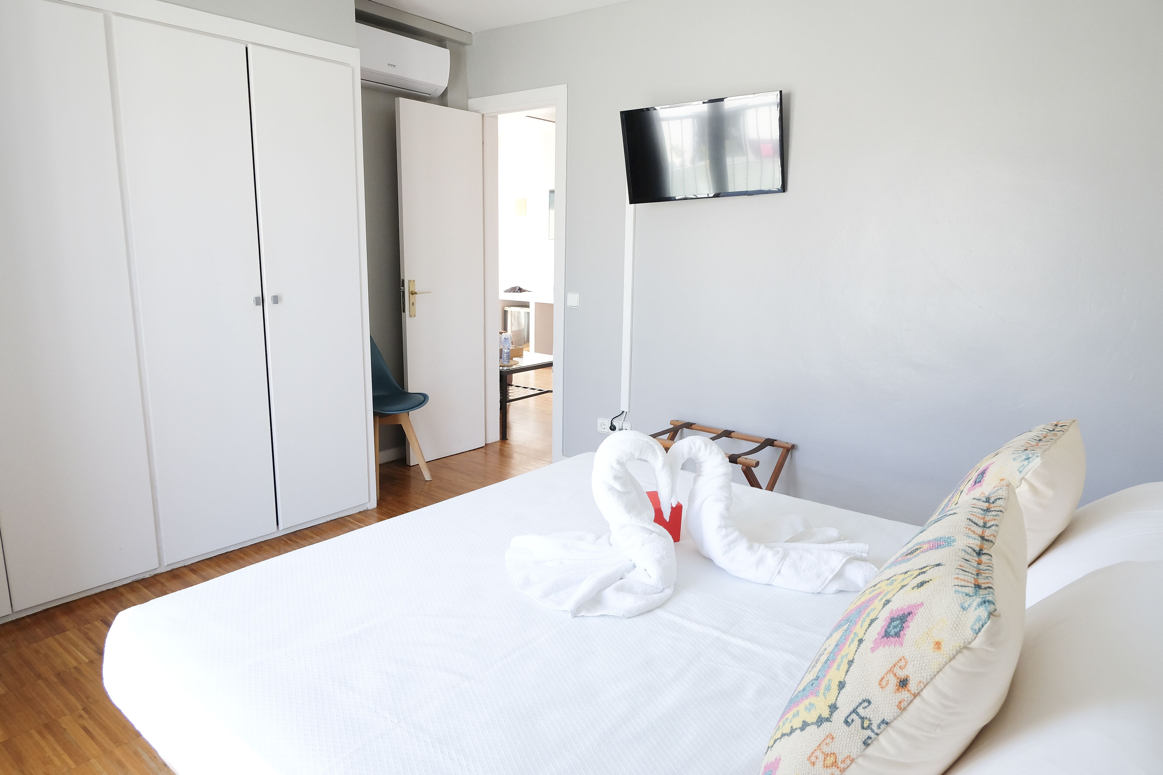Una habitación de hotel con una cama grande, un televisor montado en la pared y un armario.