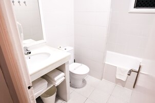 Un baño con lavamanos, inodoro y bañera blancos.