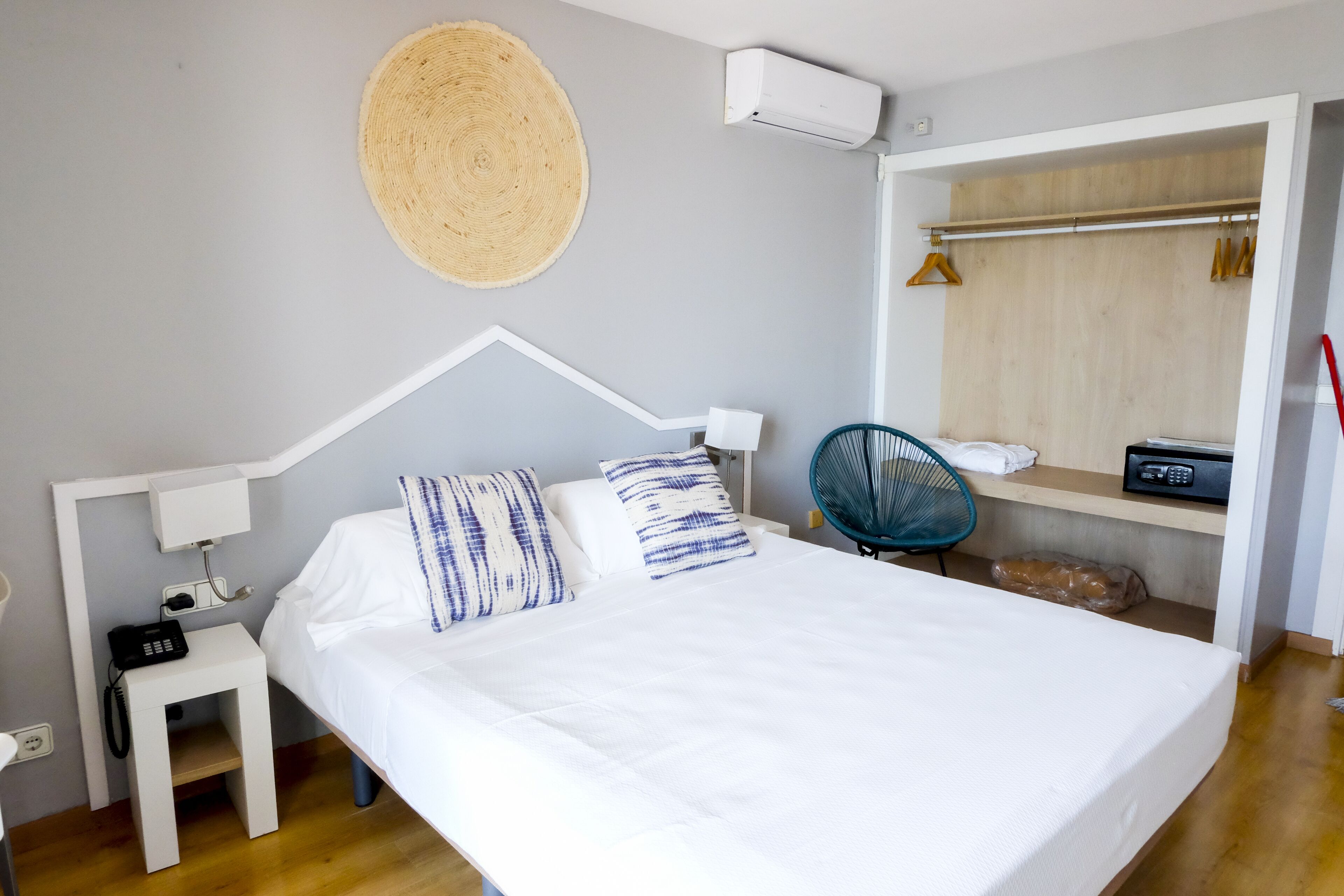 A neatly arranged bedroom with a bed, bedside table, and a small desk with a chair.