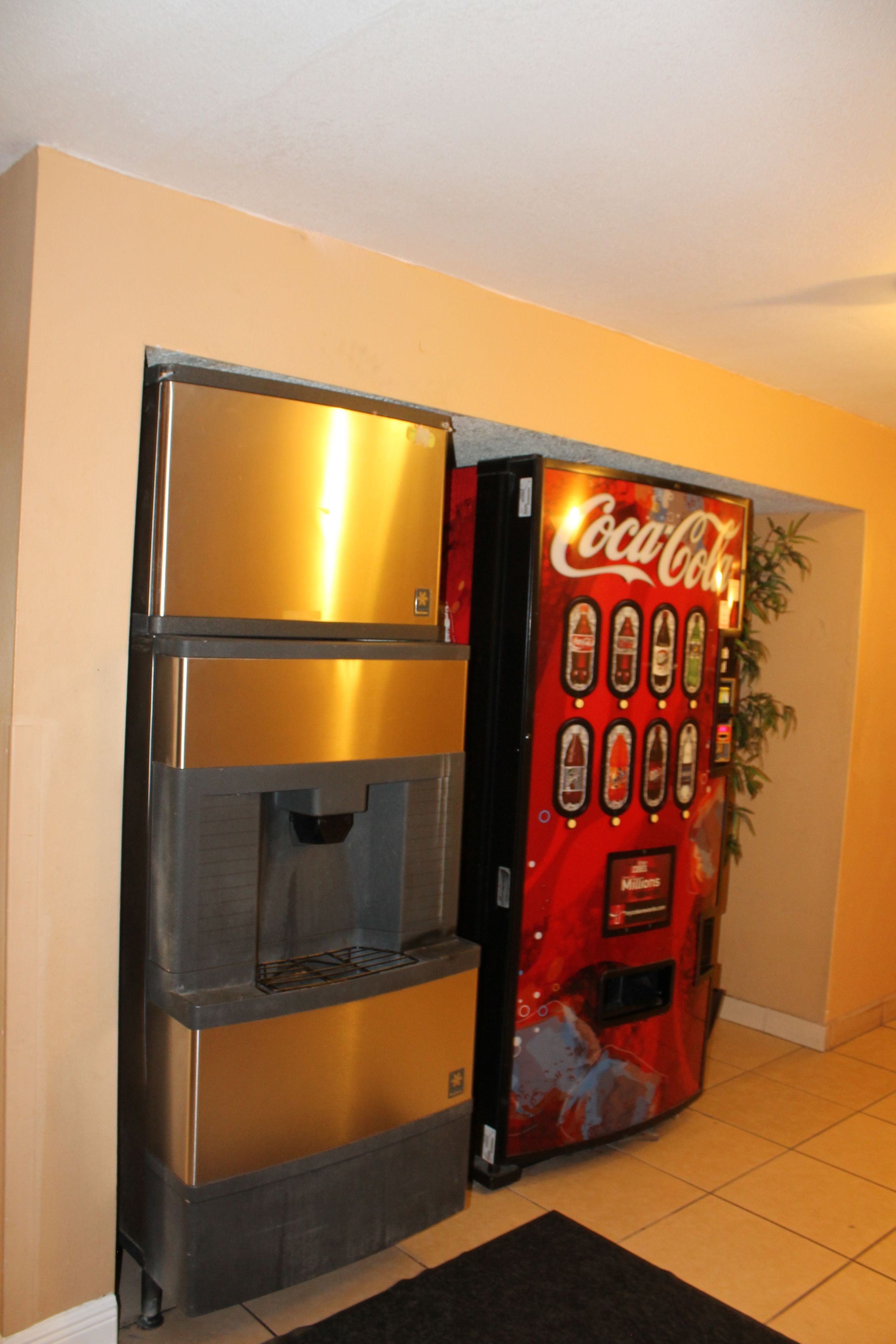 A vending machine with a Coca-Cola logo and a stainless steel refrigerator.