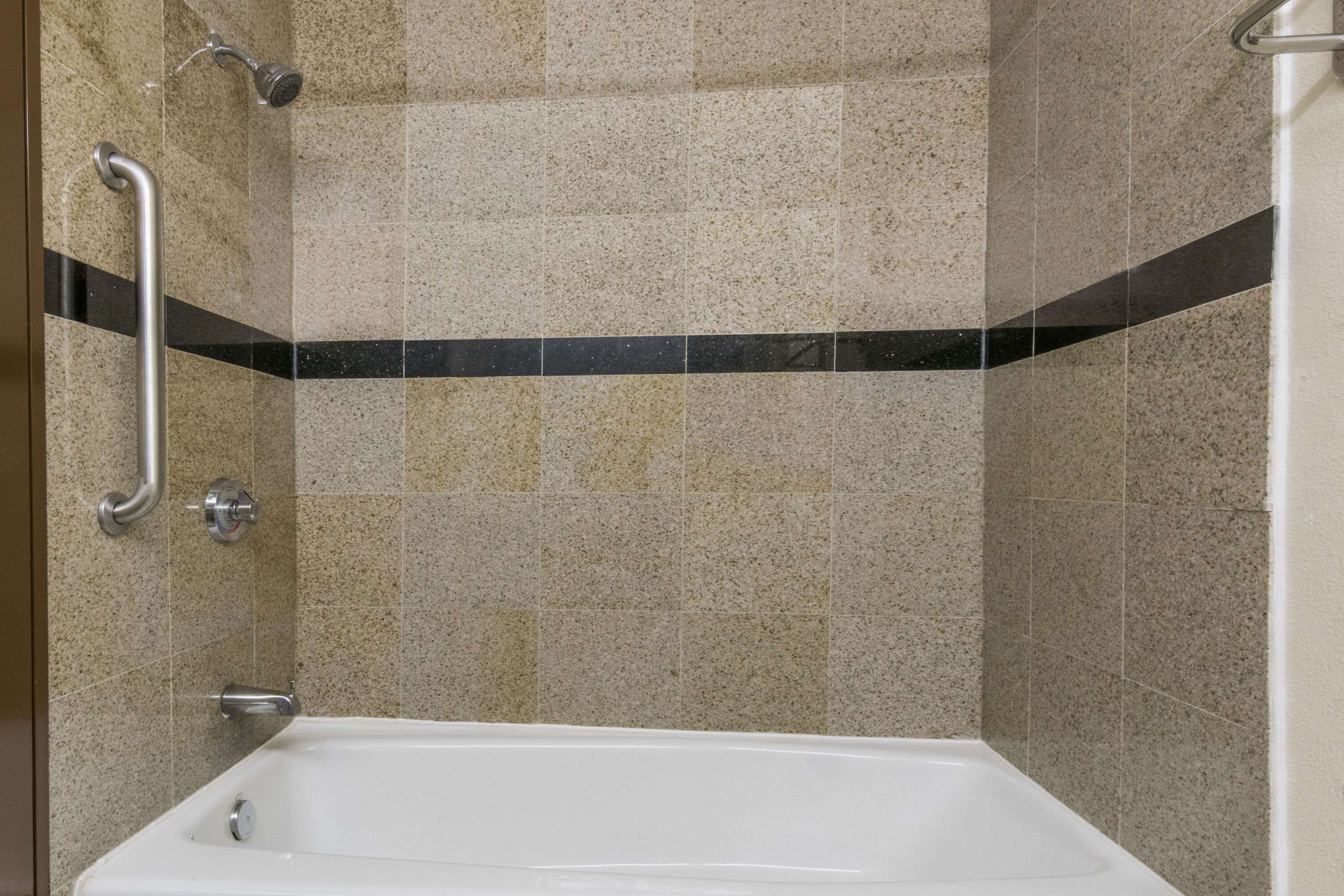 Une salle de bain équipée d’une baignoire, d’une douche et d’une barre d’appui.