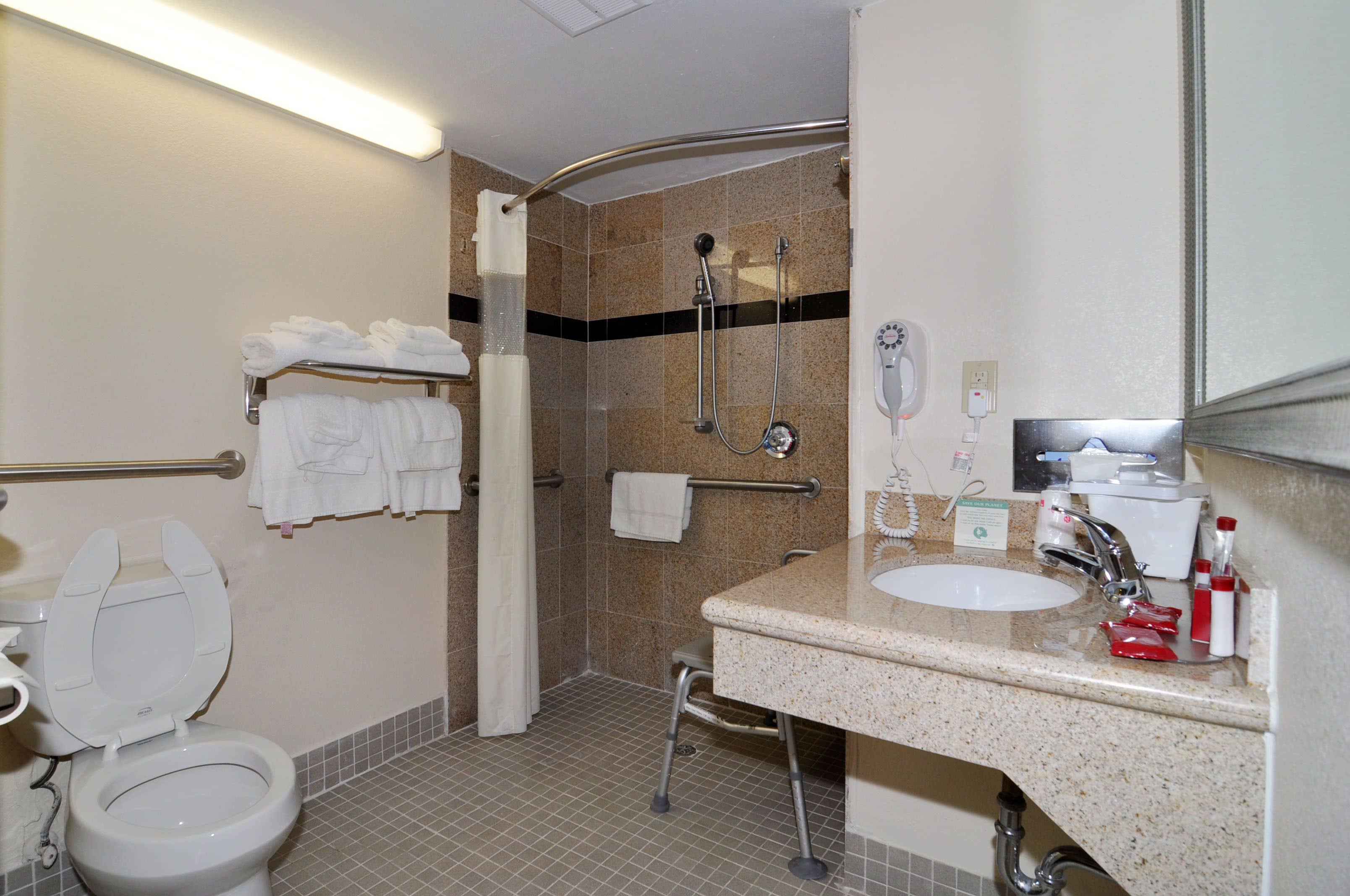 A bathroom with a toilet, sink, shower, and towel rack.