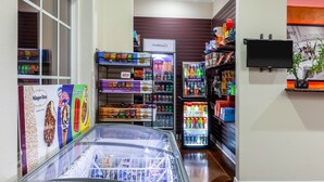 A grocery store interior with refrigerated sections, shelves stocked with snacks, and a TV mounted on the wall. - Super 8 by Wyndham Beaumont I-10 South/College St (Beaumont)