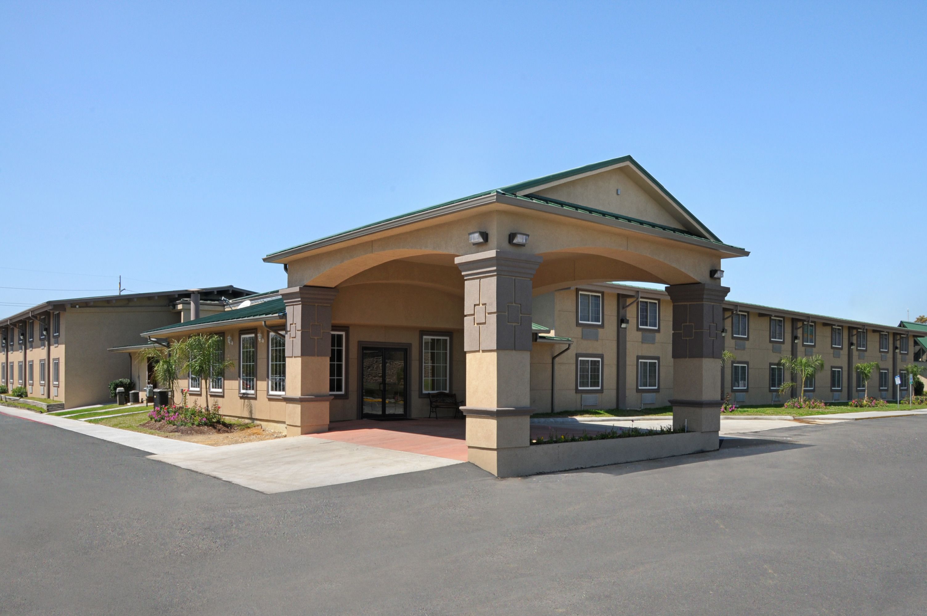A multi-story hotel with a central entrance featuring a covered walkway.