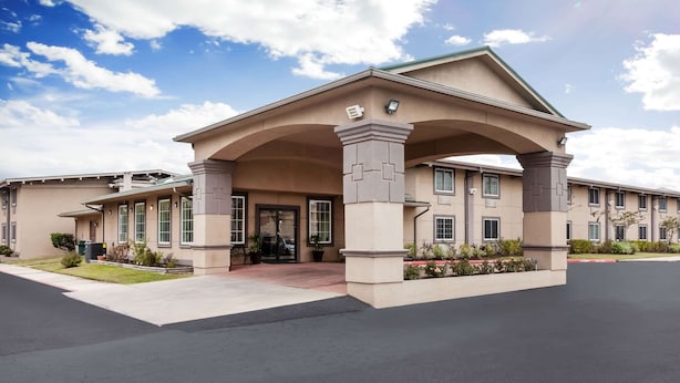 A modern hotel with a covered entrance, multiple windows, and a landscaped front yard. - Super 8 by Wyndham Beaumont I-10 South/College St (Beaumont)