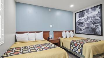 A hotel room with two beds, a nightstand, a wall-mounted phone, and a large framed picture of a waterfall.