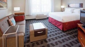 A hotel room with a bed, a sofa, a small table, a TV, and a window with curtains. - TownePlace Suites by Marriott -Minneapolis West/StLouis Park (St. Louis Park)