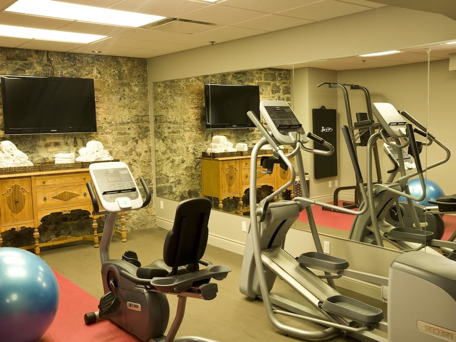 Een sportschool met trainingsapparatuur, een televisie en een spiegel.