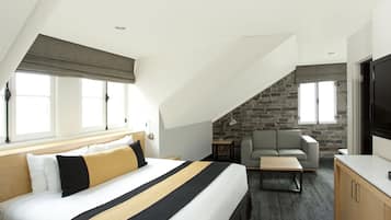 Ein Hotelzimmer mit einem großen Bett, einer Couch, einem Fernseher und einer Steinwand.