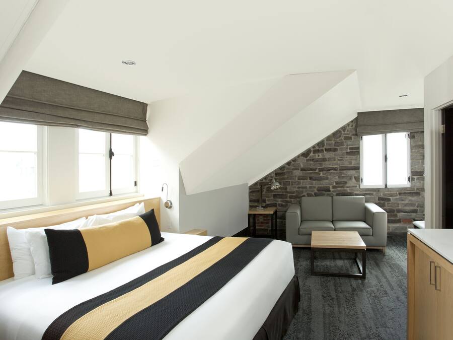 Ein Hotelzimmer mit einem großen Bett, einer Couch, einem Fernseher und einer Steinwand.