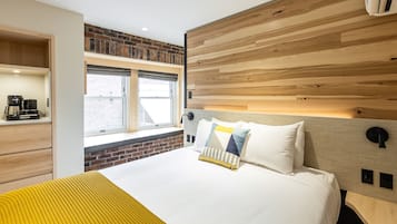 Una habitación de hotel moderna con una cama grande, un ventanal con vistas, una pared de ladrillo y un cabecero de madera.