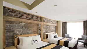 Une chambre d’hôtel avec deux lits, un mur en pierre et une vue sur l’extérieur.