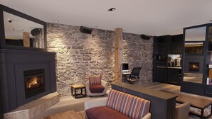 Un salon moderne avec un mur en pierre, une cheminée, un canapé et un coin repas.