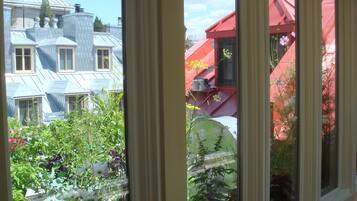Vista a través de una ventana que muestra un edificio con techo azul y otro edificio rojo al fondo.