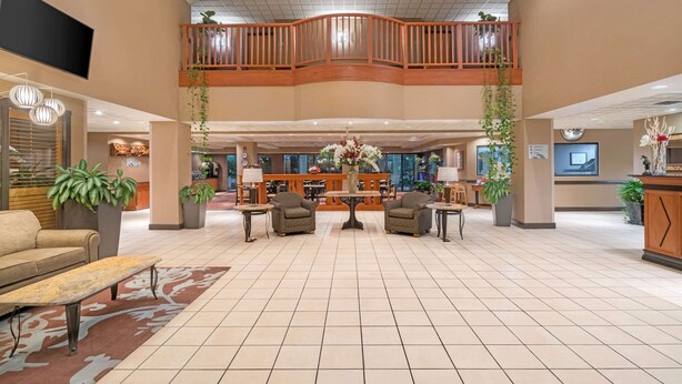 A spacious lobby with a high ceiling, a central seating area with armchairs and a coffee table, and a reception desk. - Wingate by Wyndham Lexington (Lexington)