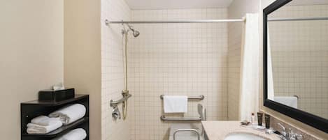 A bathroom with a sink, mirror, towel rack, and shower area.