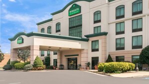 A multi-story hotel with a green and beige facade, a covered entrance, and a sign reading "Wingate by Wyndham." - Wingate by Wyndham Lexington (Lexington)