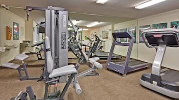 A gym with various exercise equipment including a treadmill, elliptical, and weight machines.