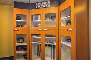 A Lendring Locker with multiple compartments, including shelves with books, kitchen appliances, and storage space. - Candlewood Suites Indianapolis by IHG (Indianapolis)