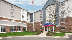 A multi-story hotel with a brick facade, a flagpole with an American flag, and a sign for Candlewood Suites.