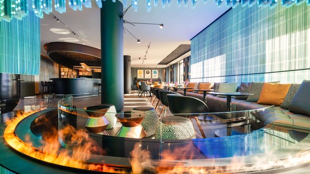 Ein stilvoller Lounge-Bereich mit Feuerstelle aus Glas, Sitzgelegenheiten und stimmungsvoller Beleuchtung.