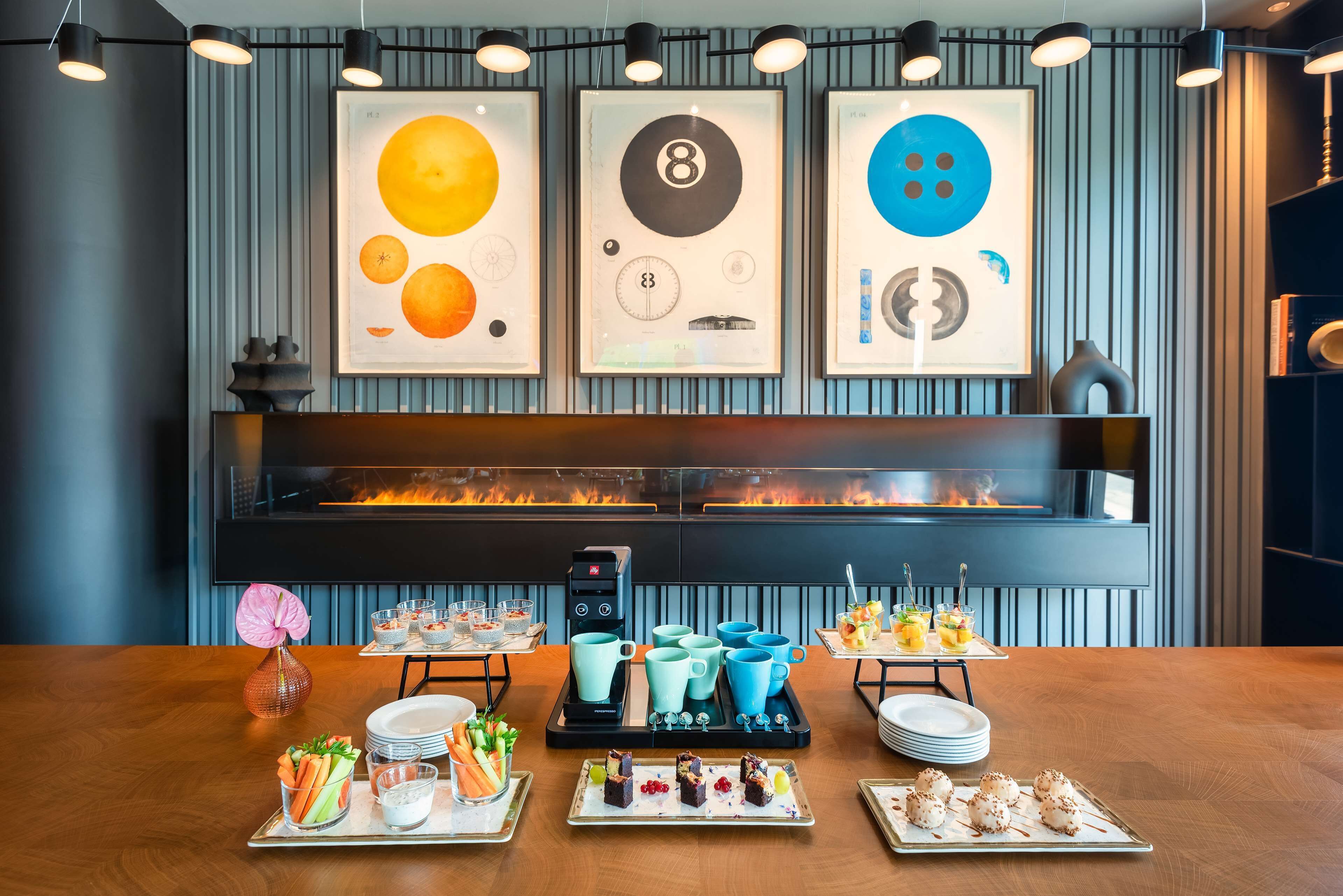 A modern dining area with a fireplace, framed artwork, and a variety of food and drink options.